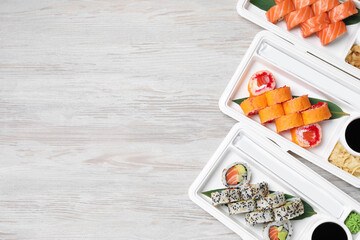 Food delivery. Plastic containers with delicious sushi on light wooden table, flat lay and space for text