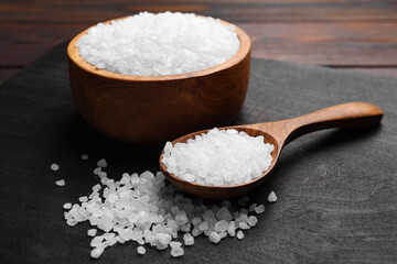 Fototapeta na wymiar Spoon and bowl of natural sea salt on wooden table