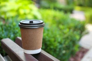 Disposable paper cup with plastic lid on wooden bench outdoors, space for text - obrazy, fototapety, plakaty