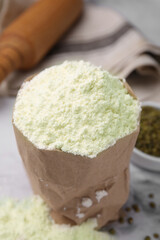 Mung bean flour in paper bag and seeds on white marble table, closeup