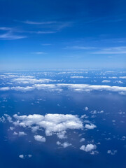 Naklejka na ściany i meble Aerial view of clouds and blue sky over ocean, cloudscape top view from airplane.