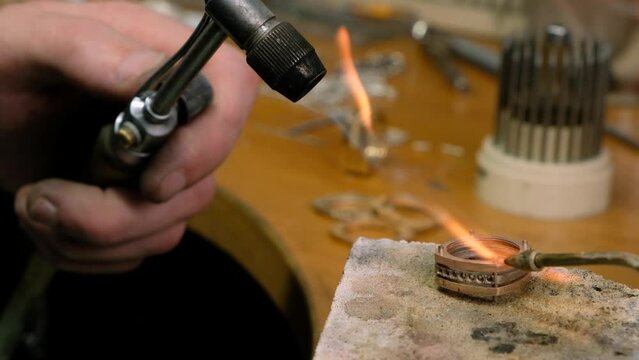 Crafting. Professional jeweler using a gas torch for a melting golden ring. Goldsmith heating metal.