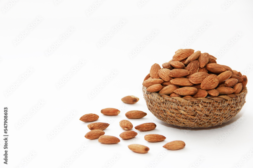 Wall mural small grains of natural brown dried almonds in a decorative plate on a white background