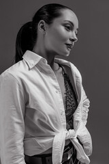 Portrait of young woman in unbuttoned shirt against gray background.