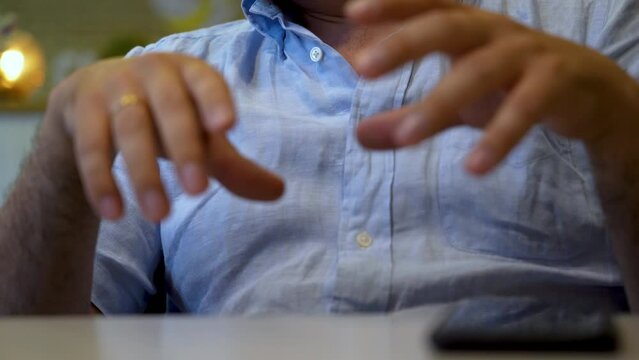 Close-up hands of unrecognizable man talking and explaining something at table, conversation or date in a cafe shop