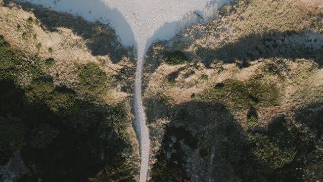 White sand road through dune landscape leading to the beach on an island. 