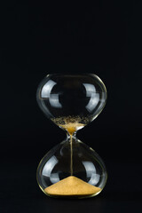 Hourglass with golden sand and black background, copy space