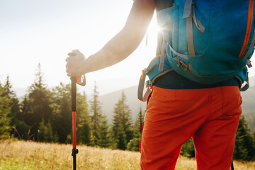 Hiker walking in mountains with poles on path in mountains. Close up of hiker sticks poles and...