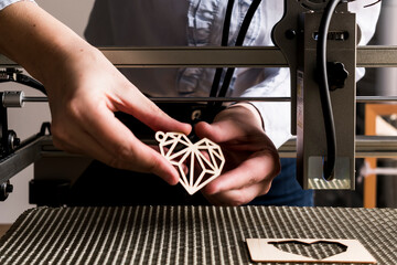 Laser engraving and cutting, woman holding an example of a cut out wooden heart