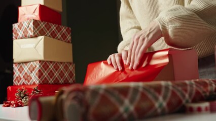 Woman in warm sweater packaging gift box with craft paper. Present for winter holidays. Christmas and Happy New Year celebrating