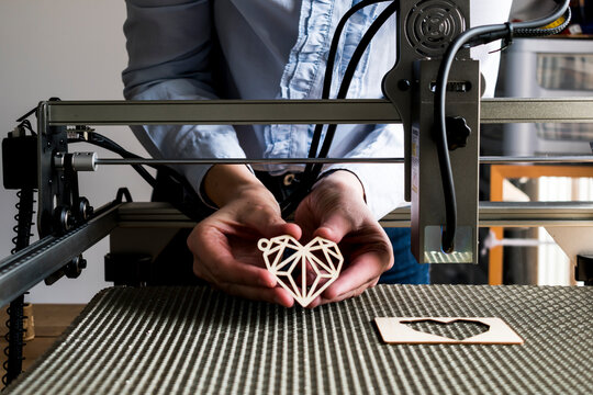 Laser engraving and cutting, woman holding an example of a cut out wooden heart
