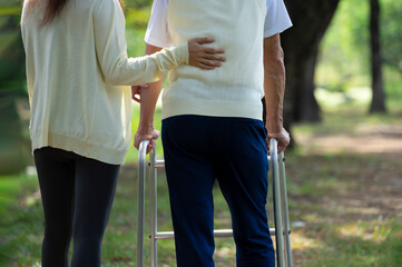 offspring or caregiver, hand support back of a disability senior man not to fall while practice...