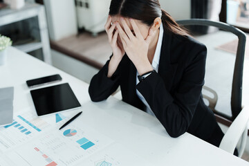 A portrait of a beautiful Asian female employee showing a stressed face while using  financial...