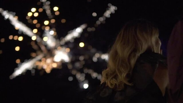 Close-up shot of a young attractive woman watching a firework display in the dark
