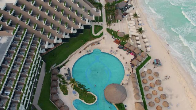 Drone aerial view of crystal blue pool and beautiful luxury resort Paradisus Cancun in Mexico with a glass roof, coastline, relaxing beach and gentle waves.