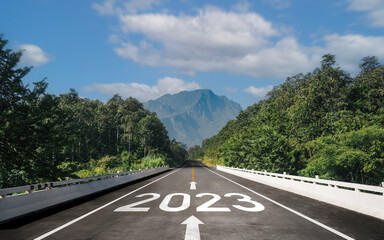 Text 2023 is written on the road and an arrow in the middle for the start of the new year from 2022...