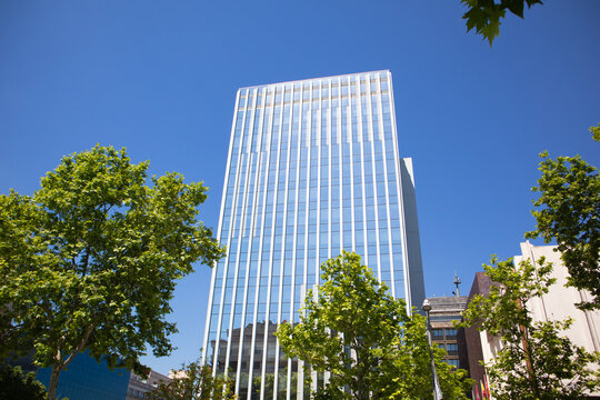 Modern tall multistory building glass facade against blue sky in summer city.