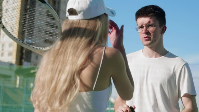 4K. A guy and a girl tennis players communicate on the tennis court.