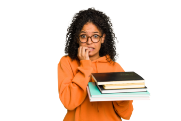 Young student woman holding a pile of books isolated biting fingernails, nervous and very anxious.