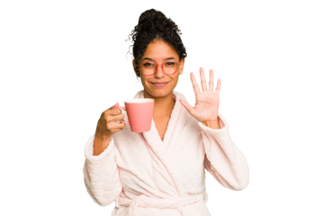 Young brazilian woman wearing a pajama holding a cup isolated smiling cheerful showing number five with fingers.