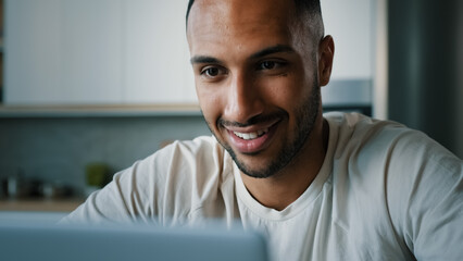 Close up front view African multiethnic man guy indoors using laptop typing chatting browsing with computer at home working remote play online game internet app shopping e-commerce website distant job