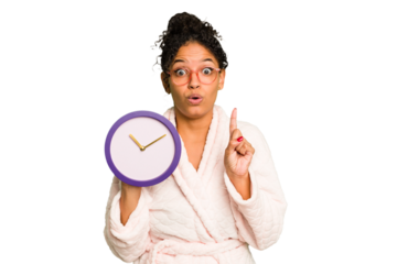 Young brazilian woman wearing a pajama holding a clock isolated having some great idea, concept of creativity.