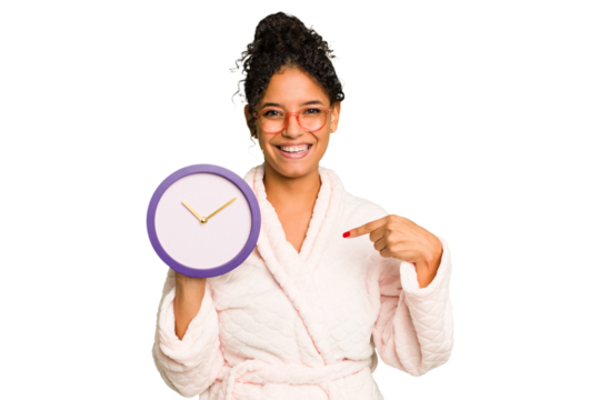 Young brazilian woman wearing a pajama holding a clock isolated person pointing by hand to a shirt copy space, proud and confident
