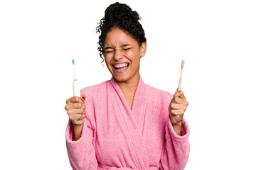Young african american woman doing a comparison between a normal toothbrush and electrical isolated...