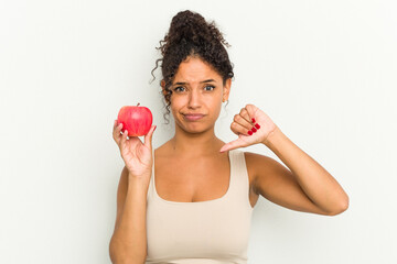 Young brazilian woman holding a red apple isolated showing a dislike gesture, thumbs down....