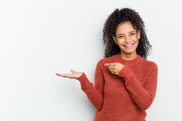 Young african american woman isolated excited holding a copy space on palm.