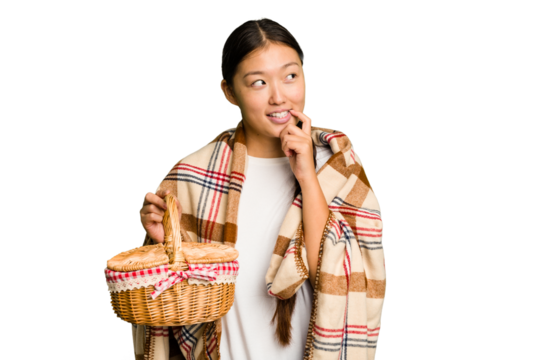 Young asian woman holding a picnic basket isolated relaxed thinking about something looking at a copy space.