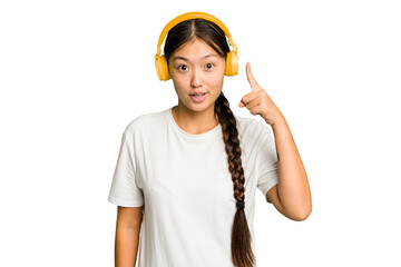 Young asian woman listening to music with headphones isolated having an idea, inspiration concept.