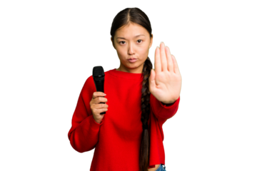 Young Chinese singer woman isolated standing with outstretched hand showing stop sign, preventing you.