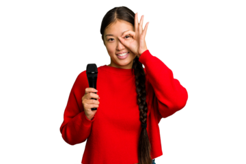 Young Chinese singer woman isolated excited keeping ok gesture on eye.