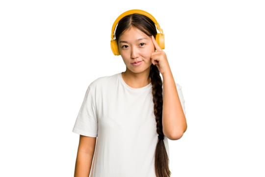 Young asian woman listening to music with headphones isolated pointing temple with finger, thinking, focused on a task. - Powered by Adobe