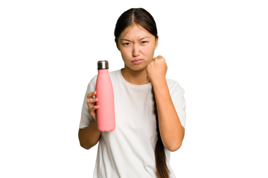 Young asian woman holding a pink thermo isolated showing fist to camera, aggressive facial expression.