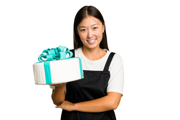 Young asian bakery holding a birthday cake isolated laughing and having fun.