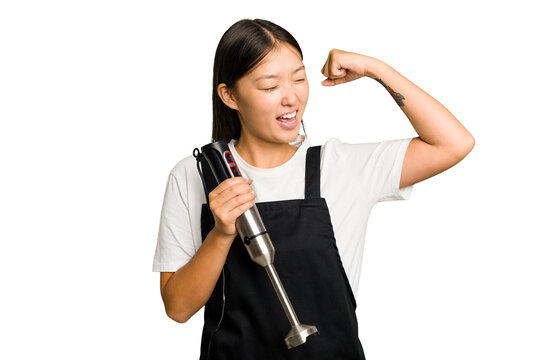 Young asian cook woman holding a blender isolated raising fist after a victory, winner concept.
