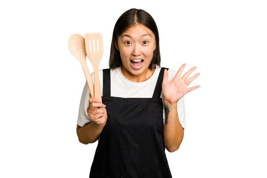 Young asian cook woman isolated receiving a pleasant surprise, excited and raising hands.