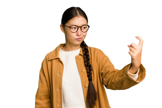 Young Asian woman isolated pointing with finger at you as if inviting come closer.