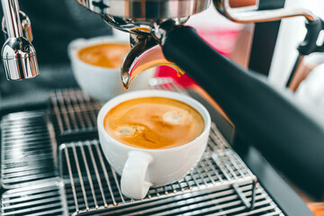 Close-up of Coffee extraction from the coffee machine with a portafilter pouring coffee into a cup, Espresso pouring from coffee machine at the coffee shop