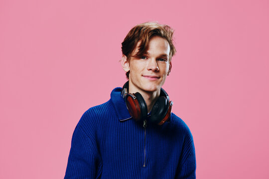 Portrait Of A Handsome Guy In A Blue Sweater With Headphones Around His Neck.