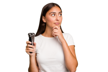 Young caucasian woman holding a razor isolated looking sideways with doubtful and skeptical expression.