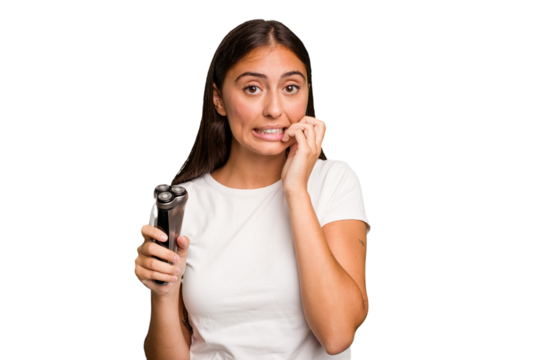 Young caucasian woman holding a razor isolated biting fingernails, nervous and very anxious.