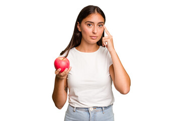 Young caucasian woman holding a red apple isolated pointing temple with finger, thinking, focused on a task.