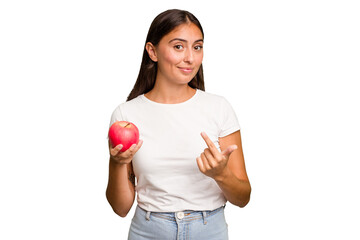 Young caucasian woman holding a red apple isolated pointing with finger at you as if inviting come closer.