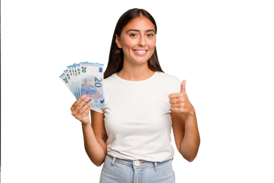 Young caucasian woman holding a banknotes isolated smiling and raising thumb up - Powered by Adobe