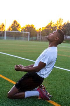 Soccer player on his knees celebrating a goal. Excited footballer man celebrating a goal.