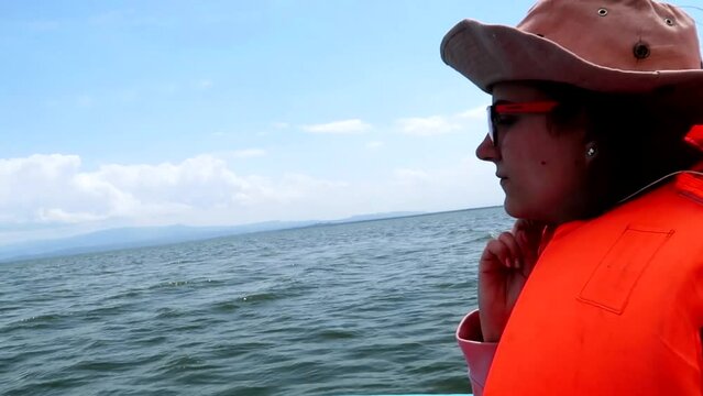 Close-up of a woman wearing an orange lifejacket on a guided tour across Lake Naivasha