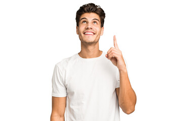 Young caucasian handsome man isolated indicates with both fore fingers up showing a blank space.